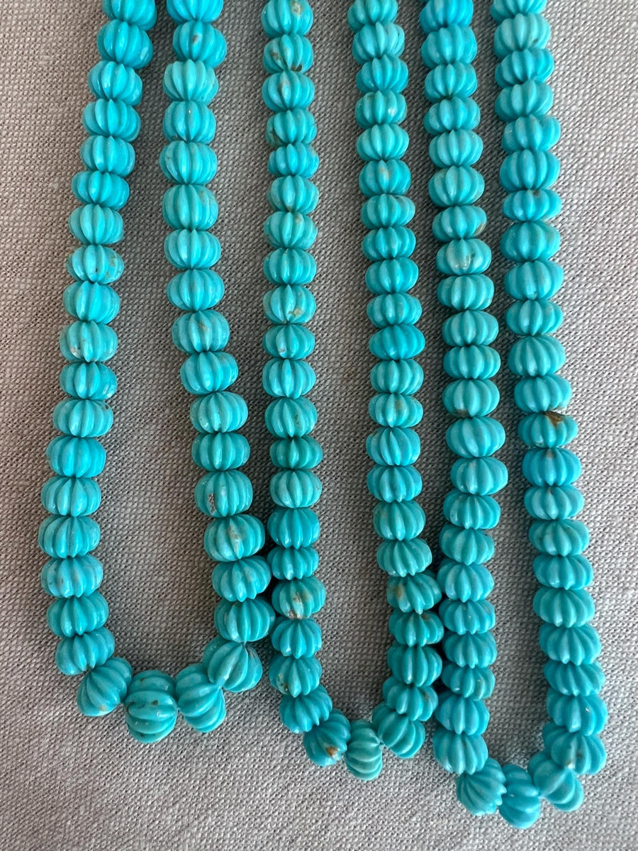 Close-up of Sleeping Beauty Turquoise carved melon beads showing beautiful blue color, natural brown matrix, and detailed pumpkin-shaped carving.