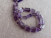 Close-up of Brazilian Amethyst cylinder beads showing rich purple color, excellent transparency, and sparkling faceted surfaces.