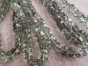 Close-up of green Prasiolite gemstone beads showing rich green color, excellent transparency, and distinctive twisted rondelle cuts.
