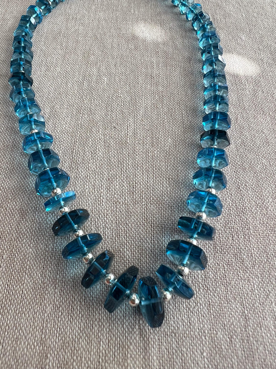Close-up of Swiss Blue Topaz gemstone beads showing vibrant blue color, exceptional clarity, and sparkling faceted bolt cuts.