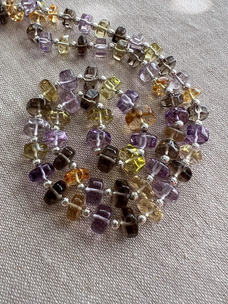 Close-up of AAA faceted button gemstone beads showing transparent purple, green, golden yellow, and lemon yellow colors.