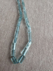 Close-up of Aquamarine faceted cylinder beads showing delicate blue color, sparkling facets, and natural gemstone inclusions.