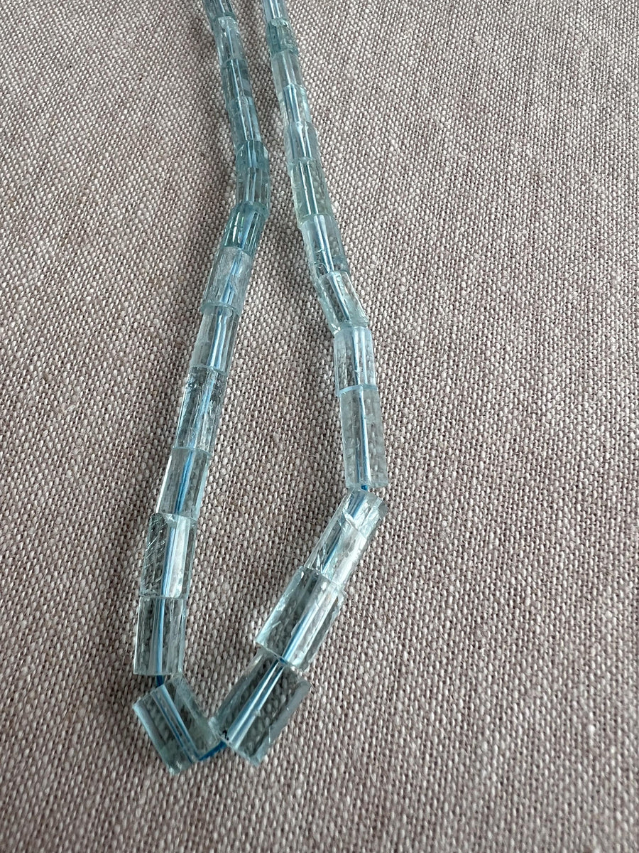 Close-up of Aquamarine faceted cylinder beads showing delicate blue color, sparkling facets, and natural gemstone inclusions.