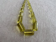 Close-up of transparent Lemon Quartz cylinder beads showing brilliant lemon yellow color, exceptional clarity, and sparkling facets.
