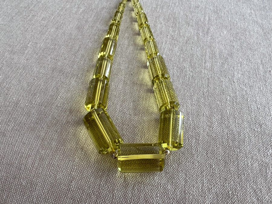 Close-up of transparent Lemon Quartz cylinder beads showing brilliant lemon yellow color, exceptional clarity, and sparkling facets.