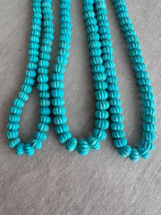 Close-up of Sleeping Beauty Turquoise carved melon beads showing beautiful blue color, natural brown matrix, and detailed pumpkin-shaped carving.