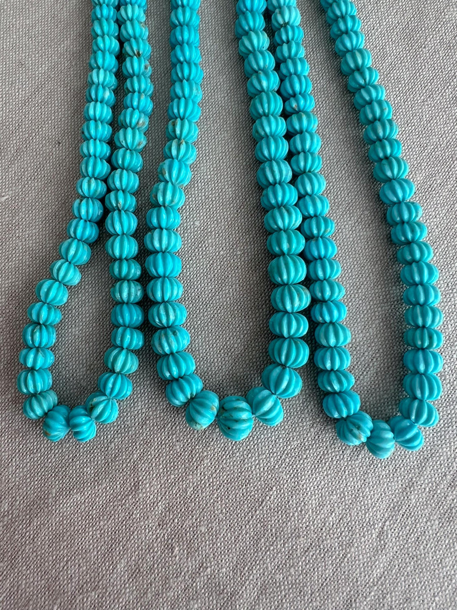 Close-up of Sleeping Beauty Turquoise carved melon beads showing beautiful blue color, natural brown matrix, and detailed pumpkin-shaped carving.