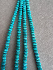 Close-up of Sleeping Beauty Turquoise melon beads showing hand-carved grooves, beautiful blue color, and natural brown matrix patterns.