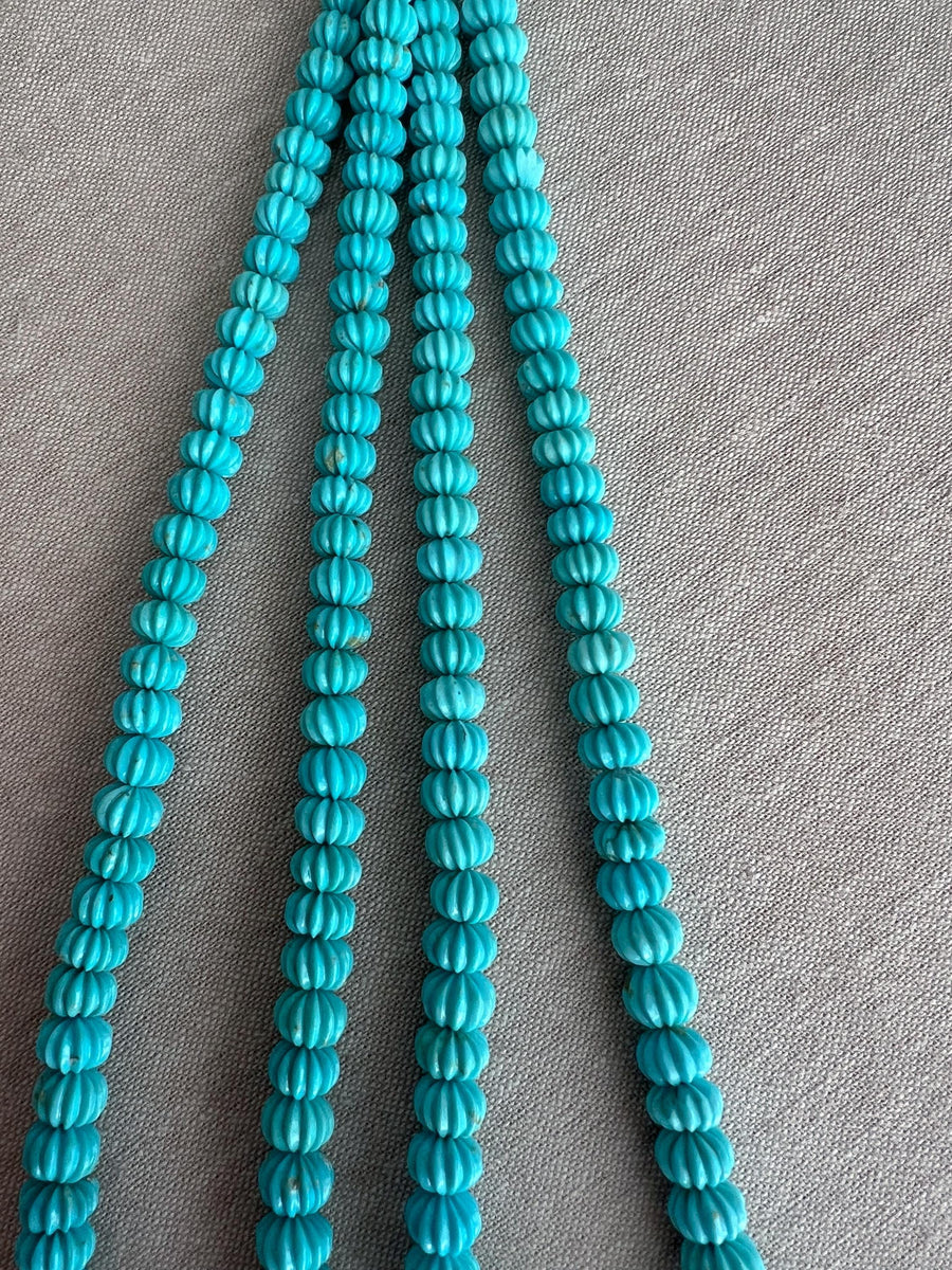 Close-up of Sleeping Beauty Turquoise melon beads showing hand-carved grooves, beautiful blue color, and natural brown matrix patterns.