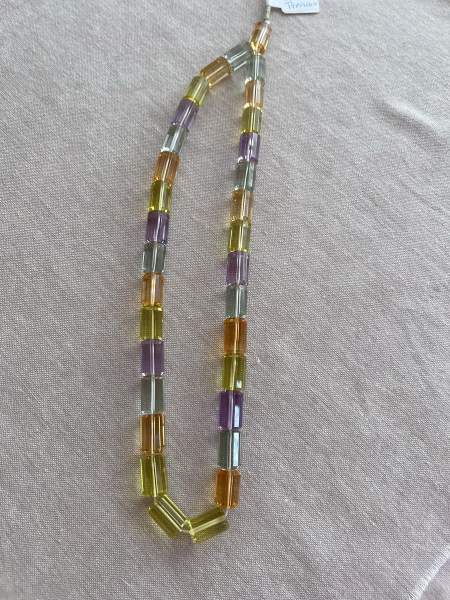 18-inch strand of mixed semi-precious faceted cylinder beads featuring 32 transparent gemstones in approximately 10x15mm sizes. orange, green, blue and purple gemstone beads