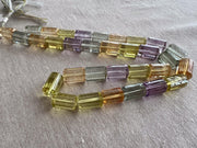 18-inch strand of mixed semi-precious faceted cylinder beads featuring 32 transparent gemstones in approximately 10x15mm sizes.