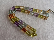18-inch strand of mixed semi-precious faceted cylinder beads featuring 32 transparent gemstones in approximately 10x15mm sizes.