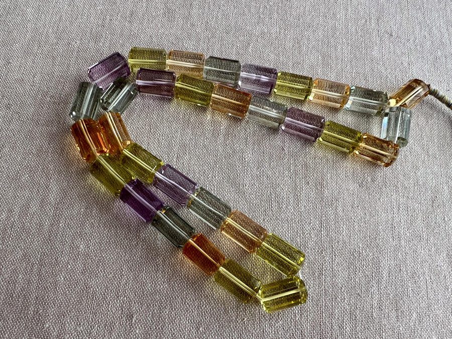 18-inch strand of mixed semi-precious faceted cylinder beads featuring 32 transparent gemstones in approximately 10x15mm sizes.
