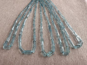 Close-up of Aquamarine faceted cylinder beads showing delicate blue color, sparkling facets, and natural gemstone inclusions.
