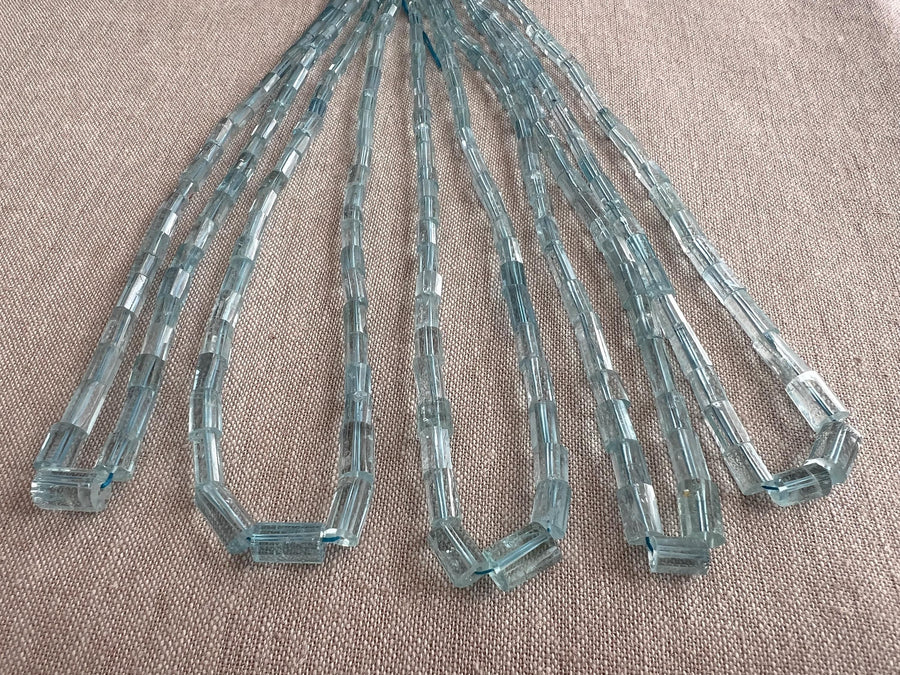 Close-up of Aquamarine faceted cylinder beads showing delicate blue color, sparkling facets, and natural gemstone inclusions.