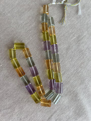 18-inch strand of mixed semi-precious faceted cylinder beads featuring 32 transparent gemstones in approximately 10x15mm sizes.