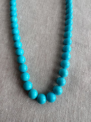 Close-up of 7mm Sleeping Beauty Turquoise beads showing uniform robin's egg blue color, smooth polish, and no visible matrix.