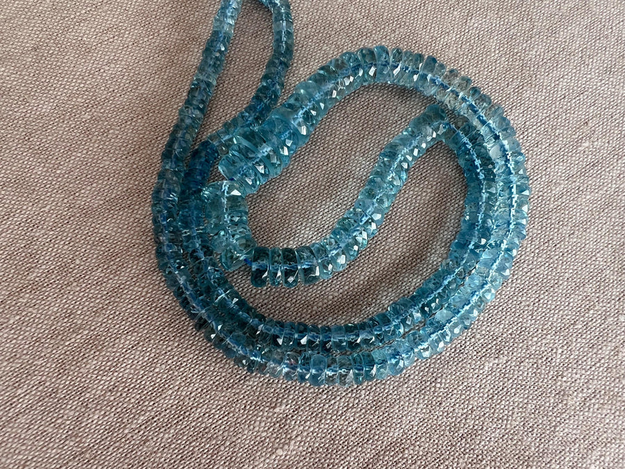 Close-up of transparent Santa Maria Aquamarine beads showing exceptional deep blue color, clarity, and sparkling facets.