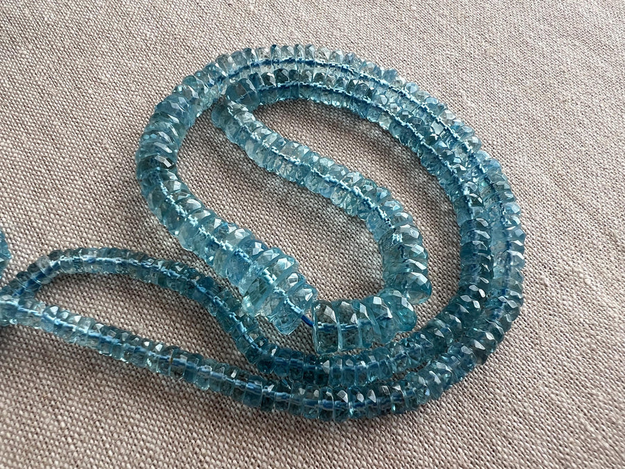 Close-up of transparent Santa Maria Aquamarine beads showing exceptional deep blue color, clarity, and sparkling facets.