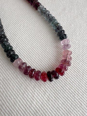 close up detail view AAA natural Spinel gemstone beads with carved rondelle shapes in mixed pink, red, and gray tones.