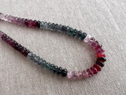 AAA natural Spinel gemstone beads with carved rondelle shapes in mixed pink, red, and gray tones. detail shot