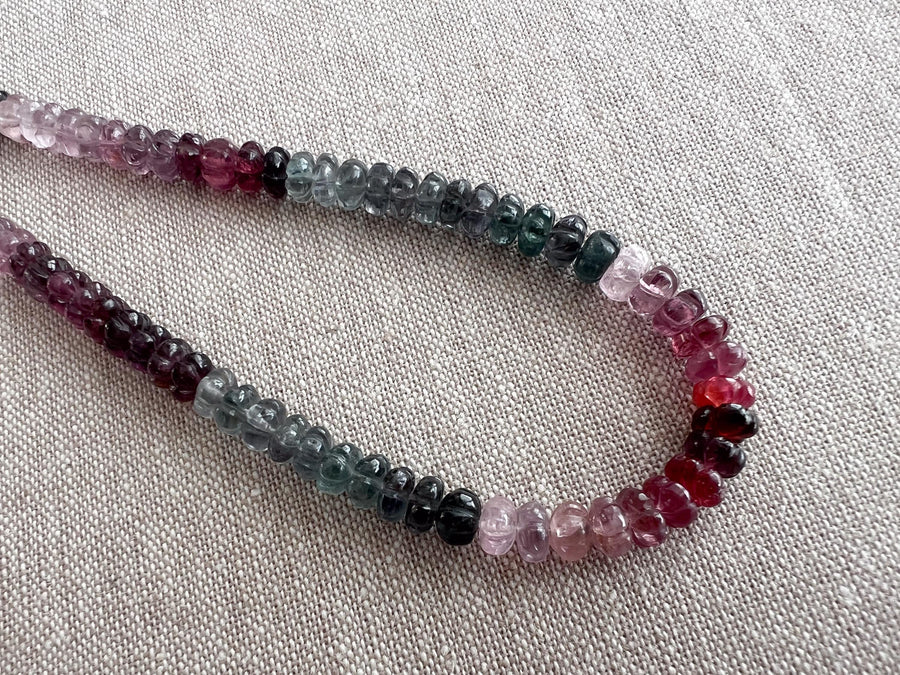 AAA natural Spinel gemstone beads with carved rondelle shapes in mixed pink, red, and gray tones. detail shot