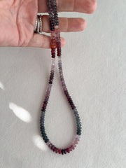 hand holding AAA natural multi-color Spinel carved rondelle gemstone beads, 5mm–6mm, for jewelry making.