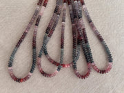 Close-up of AAA carved Spinel rondelle beads showing natural pink, red, and gray gemstone colors. multiple strands, 5 strands total