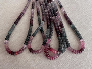 Close-up of AAA carved Spinel rondelle beads showing natural pink, red, and gray gemstone colors. multiple strands close up view