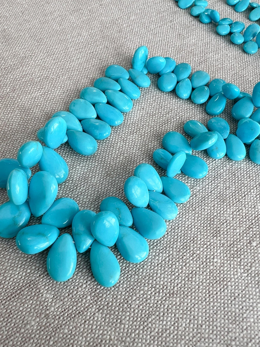 Smooth almond-shaped Sleeping Beauty turquoise beads showing natural Arizona turquoise color and polished surfaces.