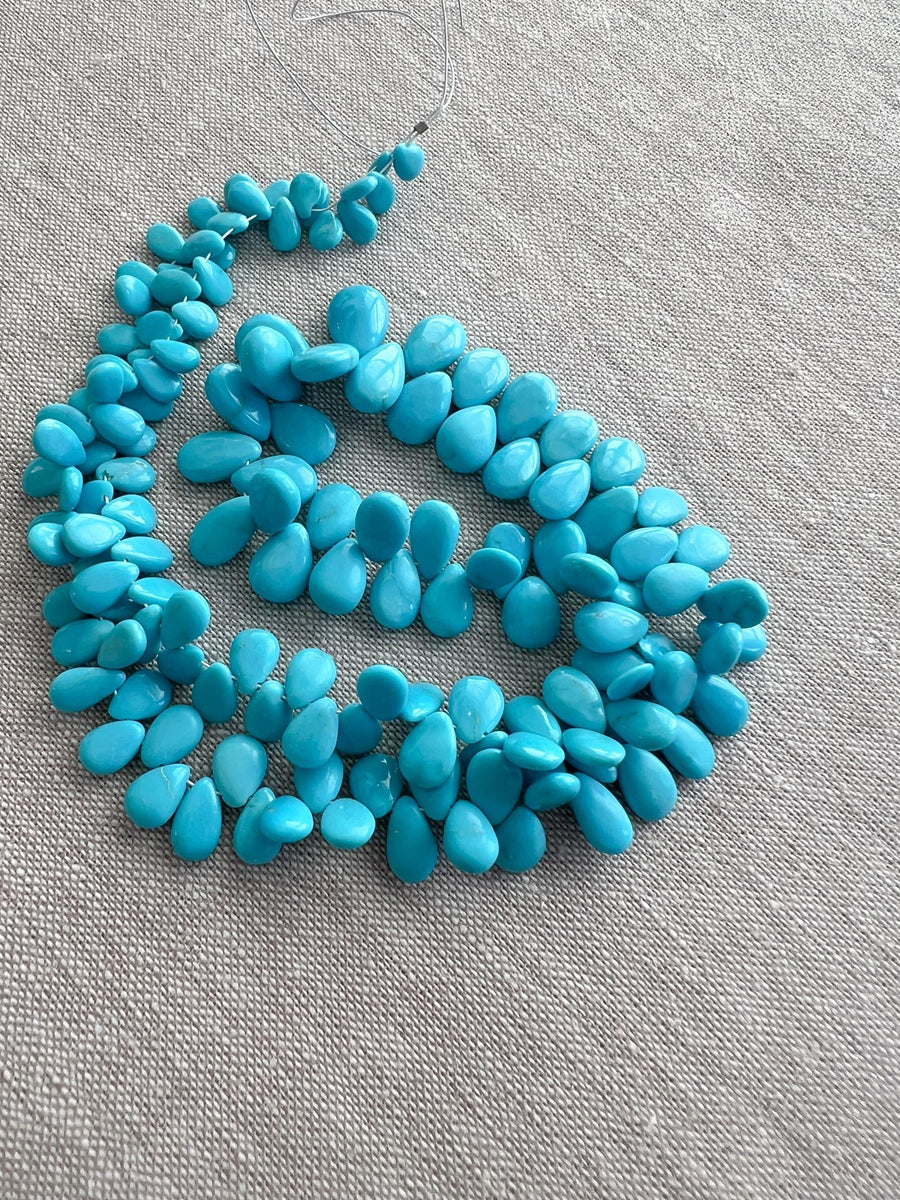 AAA-grade natural Sleeping Beauty turquoise smooth almond-shaped gemstones from Arizona, featuring classic robin's egg blue color and a polished finish.