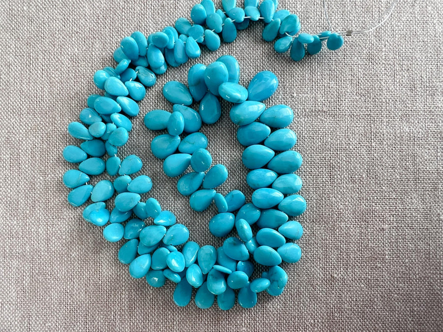 Smooth almond-shaped Sleeping Beauty turquoise beads showing natural Arizona turquoise color and polished surfaces.