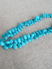 Smooth almond-shaped Sleeping Beauty turquoise beads showing natural Arizona turquoise color and polished surfaces.