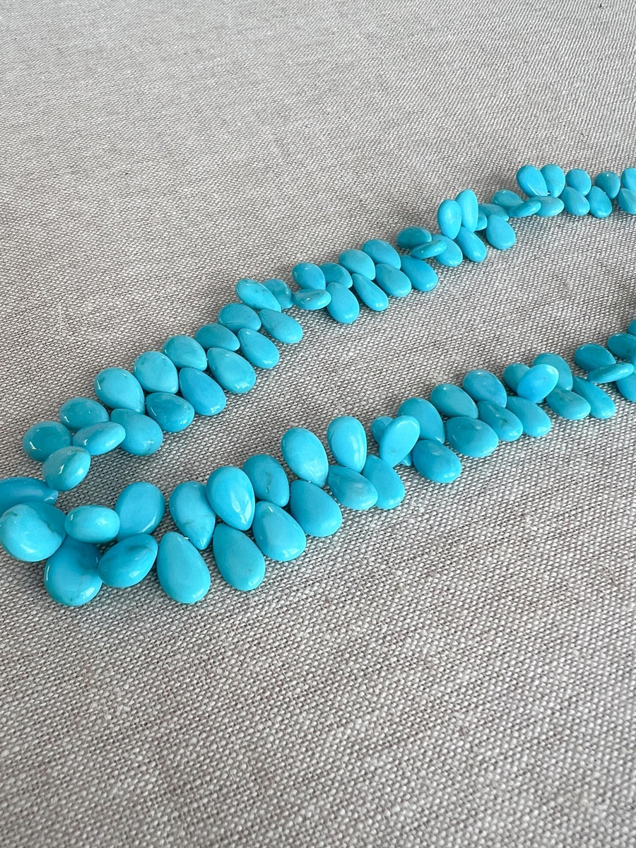 Smooth almond-shaped Sleeping Beauty turquoise beads showing natural Arizona turquoise color and polished surfaces.
