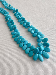 Smooth almond-shaped Sleeping Beauty turquoise beads showing natural Arizona turquoise color and polished surfaces.