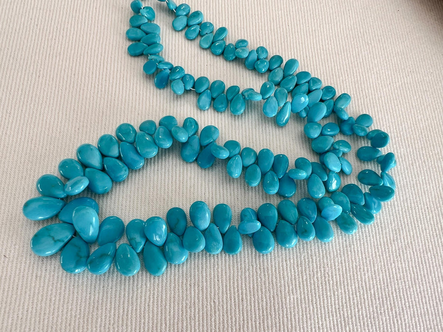 Smooth almond-shaped Sleeping Beauty turquoise beads showing natural Arizona turquoise color and polished surfaces, full strand