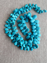 Smooth almond-shaped Sleeping Beauty turquoise beads showing natural Arizona turquoise color and polished surfaces, full strand