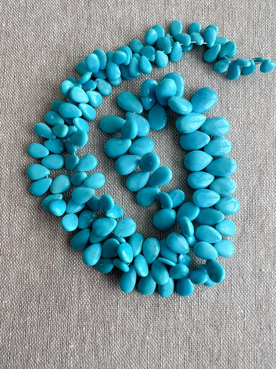 Smooth almond-shaped Sleeping Beauty turquoise beads showing natural Arizona turquoise color and polished surfaces, full strand