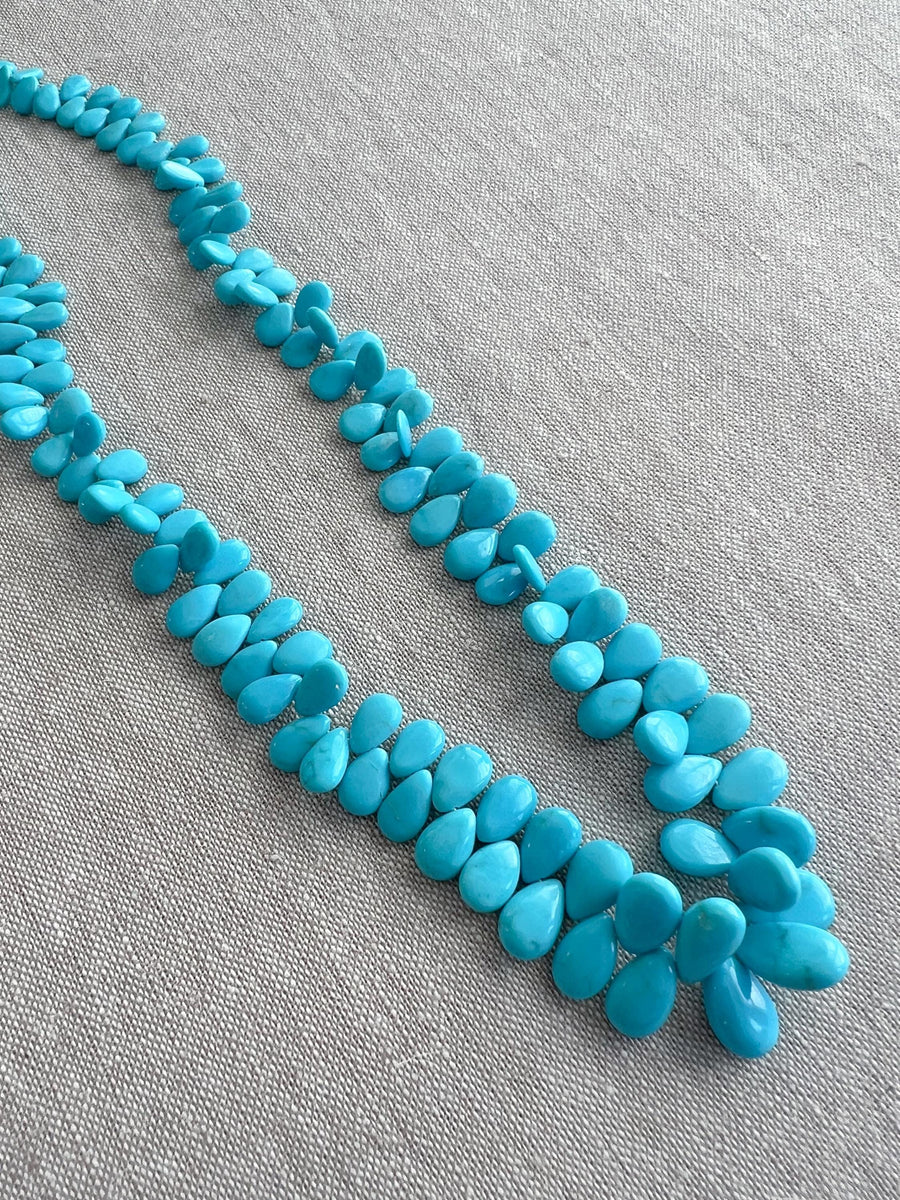 Smooth almond-shaped Sleeping Beauty turquoise beads showing natural Arizona turquoise color and polished surfaces.