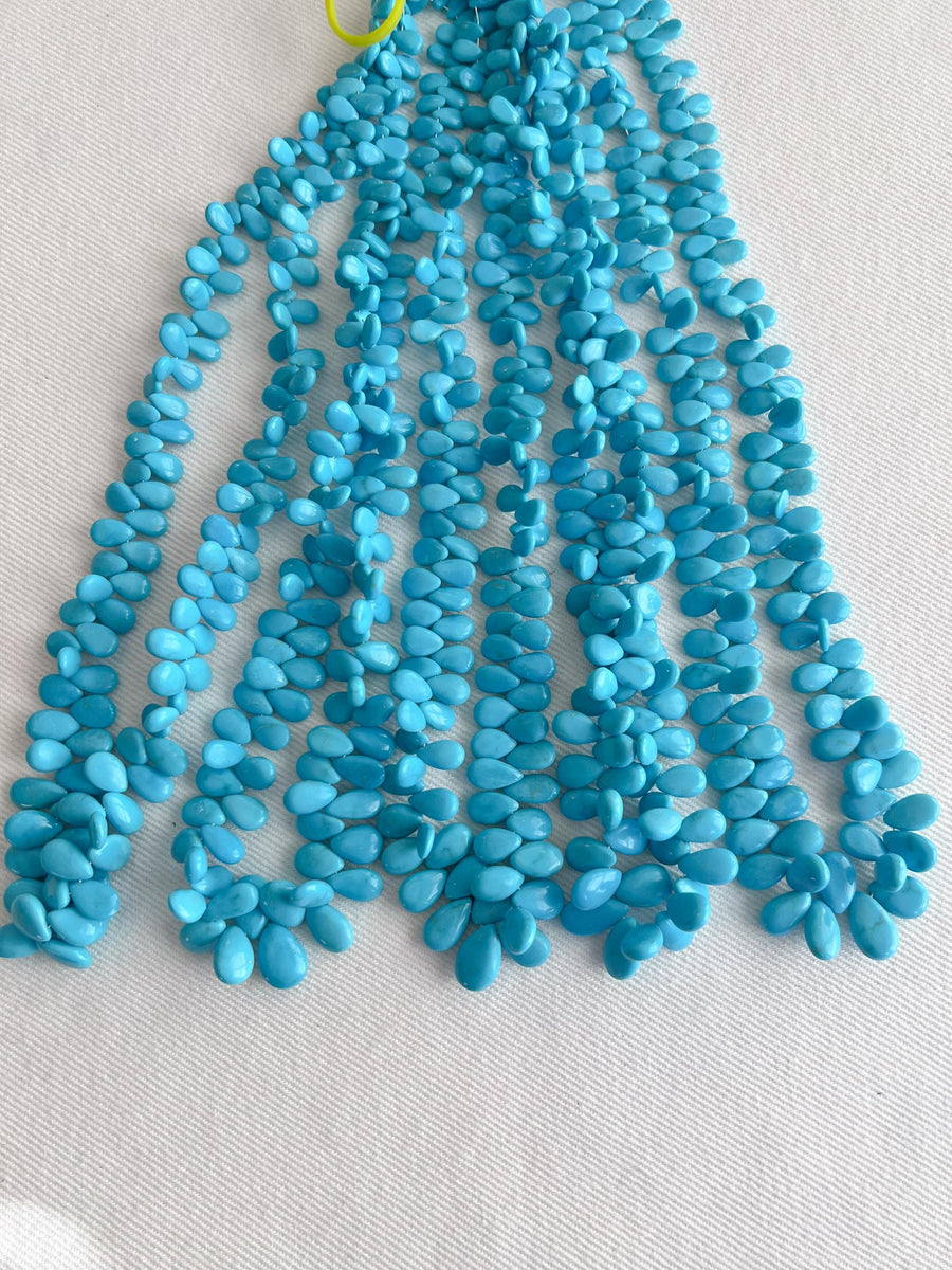 Smooth almond-shaped Sleeping Beauty turquoise beads showing natural Arizona turquoise color and polished surfaces. multiple strands