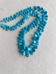 Smooth almond-shaped Sleeping Beauty turquoise beads showing natural Arizona turquoise color and polished surfaces.