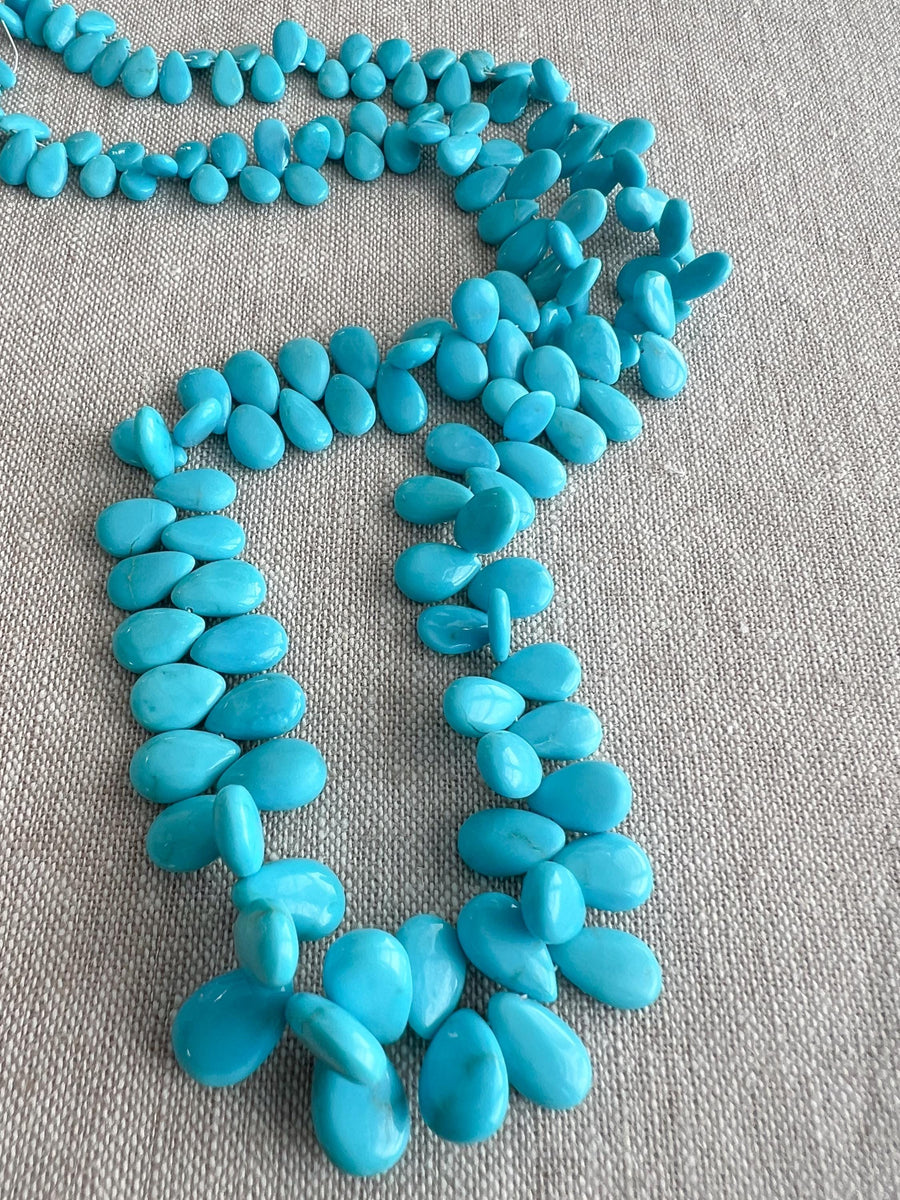 Smooth almond-shaped Sleeping Beauty turquoise beads showing natural Arizona turquoise color and polished surfaces.