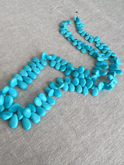 Smooth almond-shaped Sleeping Beauty turquoise beads showing natural Arizona turquoise color and polished surfaces.