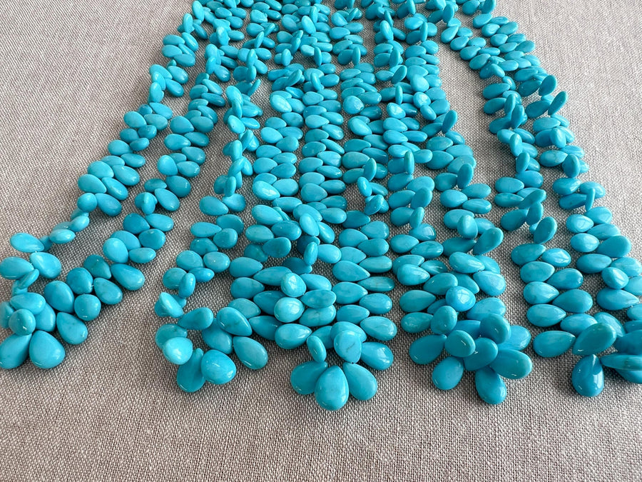 Smooth almond-shaped Sleeping Beauty turquoise beads showing natural Arizona turquoise color and polished surfaces. multiple strands