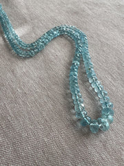 Close-up of AAA Aquamarine faceted rondelle beads showing transparent blue gemstones, excellent clarity, and sparkling hand-cut facets.